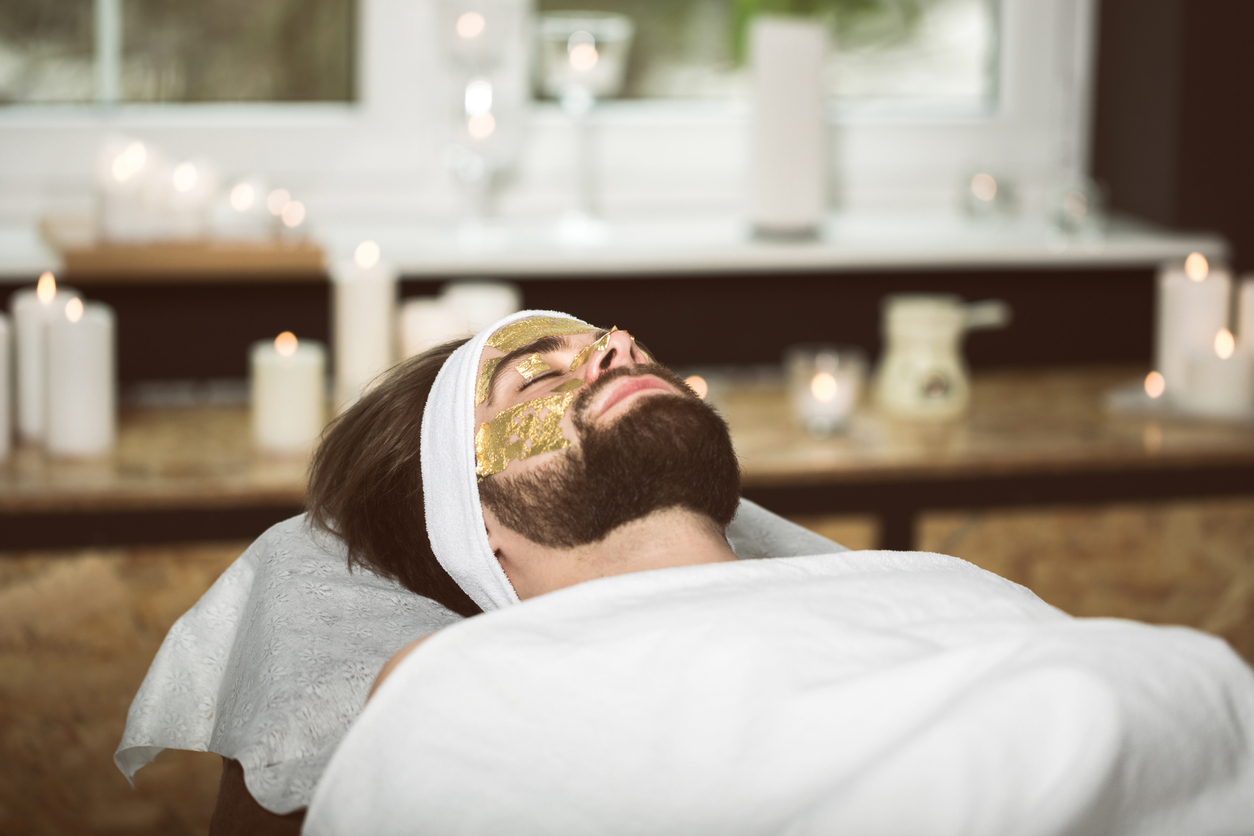 Man at beautician's during gold mask anti-aging therapy
