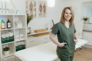 Healthcare time. happy female medical massage therapist in massage cabinet looking at camera.