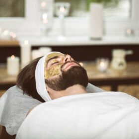 Man at beautician's during gold mask anti-aging therapy